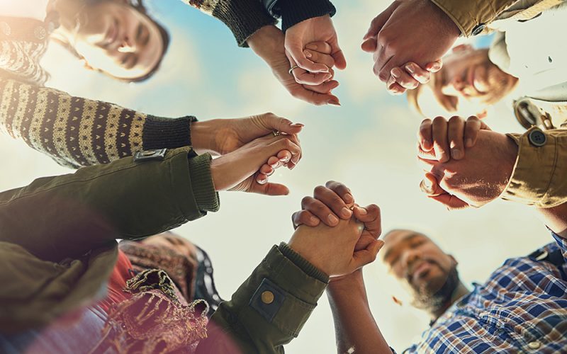 Shot of a group of friends putting their hands together in prayer