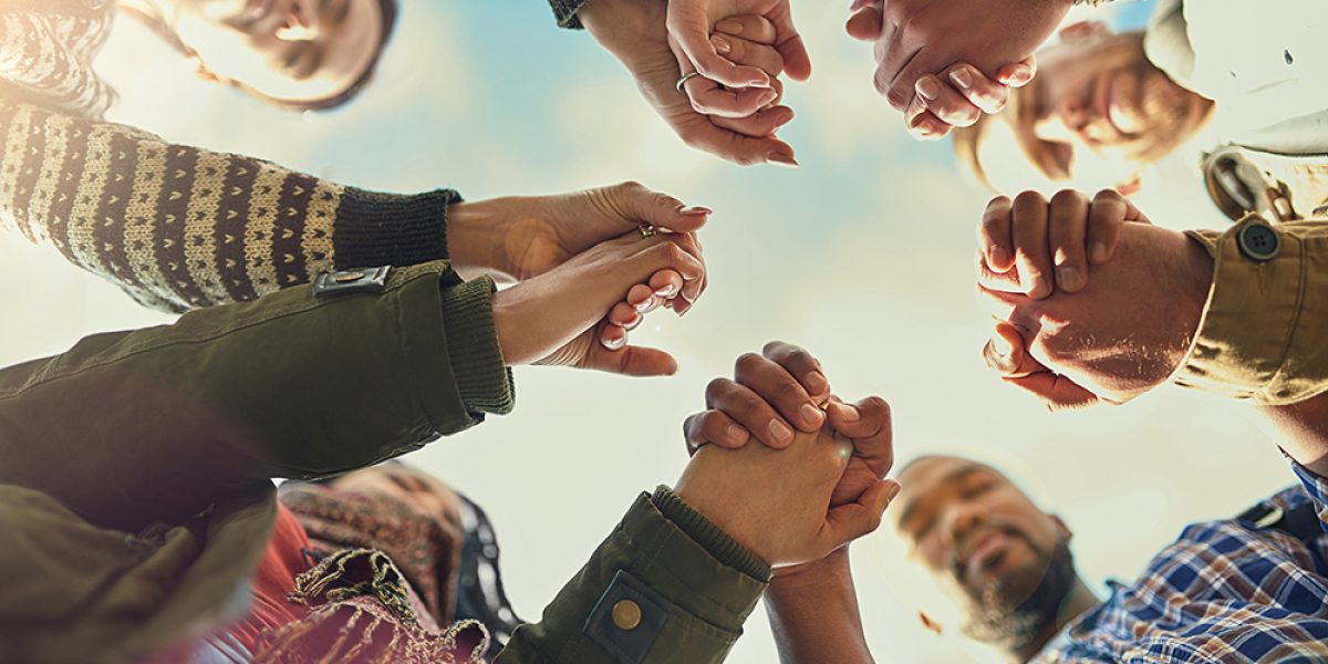 Shot of a group of friends putting their hands together in prayer