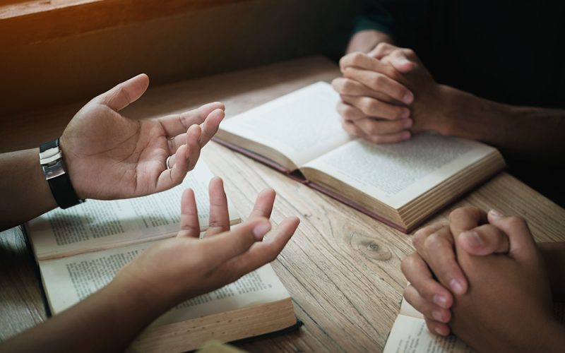 Christians are congregants join hands to pray and seek the blessings of God. Devotional or prayer meeting concept.