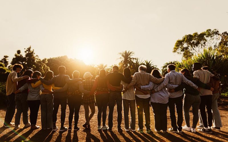 Back view of happy multigenerational people having fun in a public park during sunset time - Community and support concept