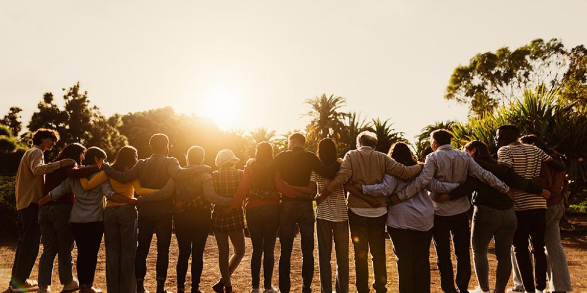 Back view of happy multigenerational people having fun in a public park during sunset time - Community and support concept