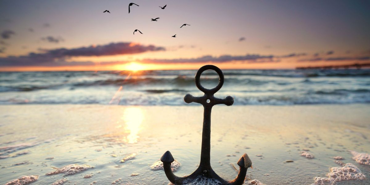 anchor at the beach with sunset light with flying birds on the sky