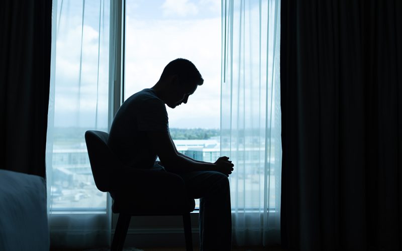 Lonely and sad man sitting in the dark room by  himself.