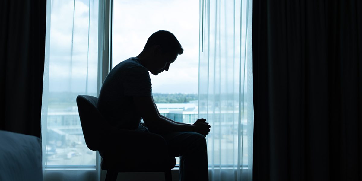 Lonely and sad man sitting in the dark room by  himself.