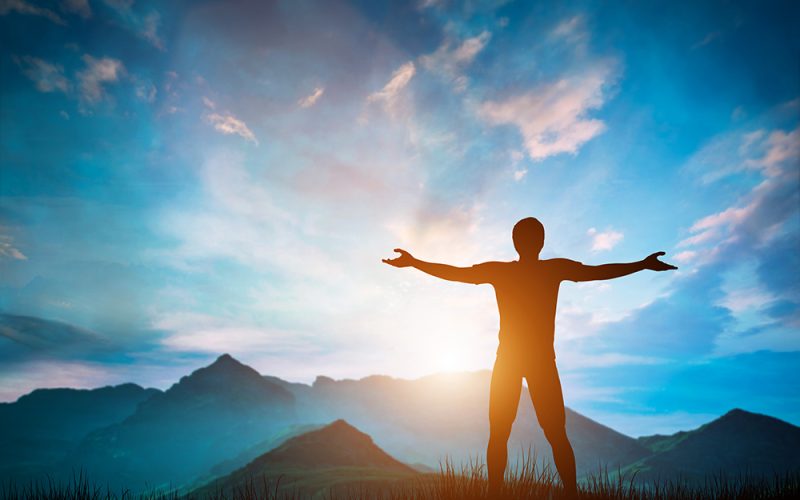 Man standing with arms raised looking at wonderful mountains landscape at sunset. Nature inspiration, happiness, freedom concepts. 3D illustration